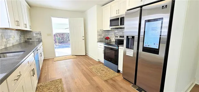 a kitchen with stainless steel appliances granite countertop a refrigerator a stove top oven a sink and dishwasher