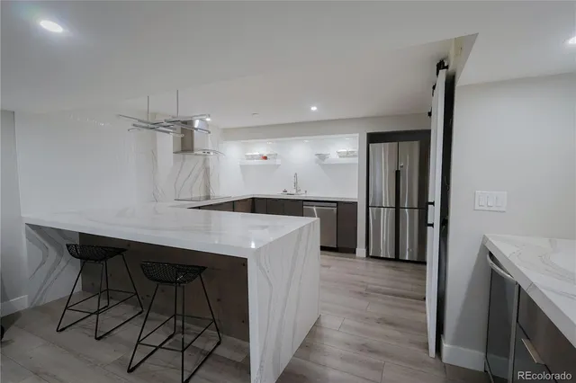 a kitchen with kitchen island a counter top space wooden floor and a refrigerator