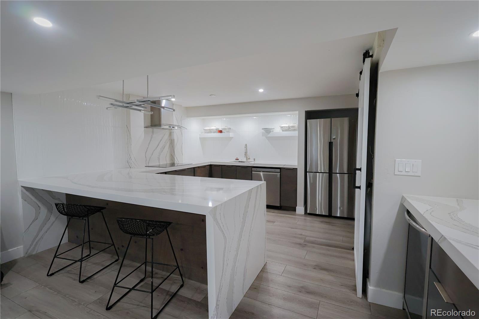 5661 West Lakeridge Road Denver, CO 80227 - Photo 28 of 48 a kitchen with kitchen island a counter top space wooden floor and a refrigerator