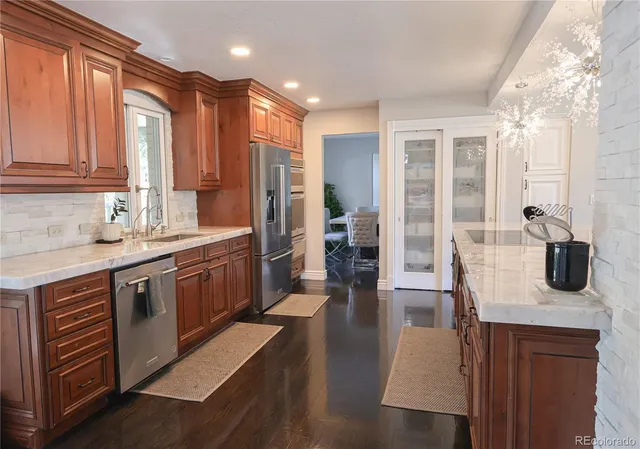 a kitchen with stainless steel appliances granite countertop a sink a stove and a refrigerator
