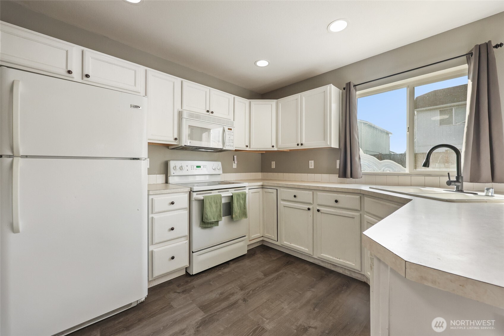 9826 Greenleaf Loop Southeast Yelm, WA 98597 - Photo 13 of 36 a kitchen with white cabinets sink and white appliances