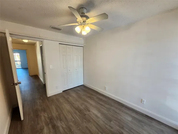 an empty room with wooden floor and a ceiling fan
