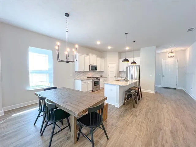 a view of a dining room and livingroom with furniture wooden floor a chandelier