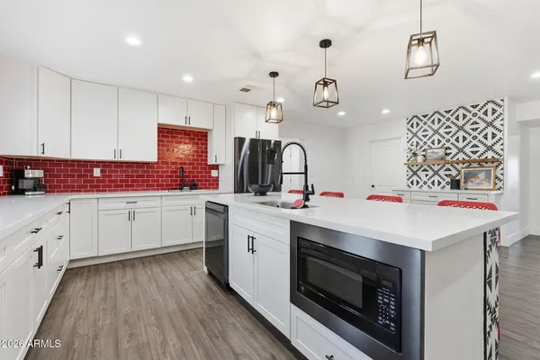 a kitchen with stainless steel appliances kitchen island granite countertop a table chairs and a refrigerator