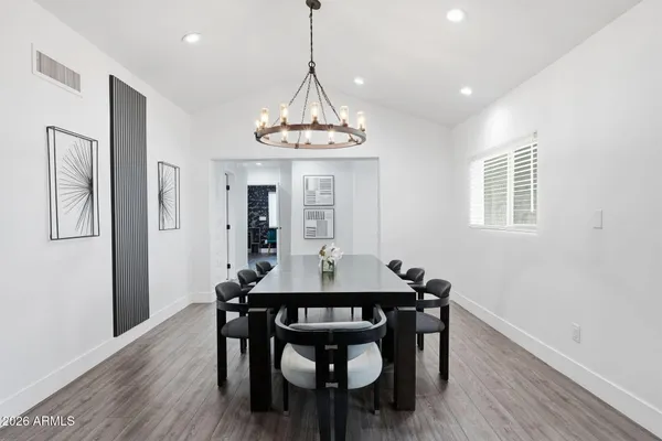a dining room with wooden floor a chandelier a wooden table and chairs