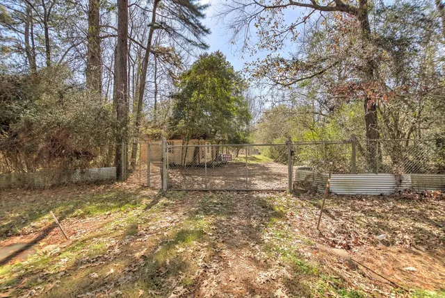 a view of a backyard with wooden fence and large trees