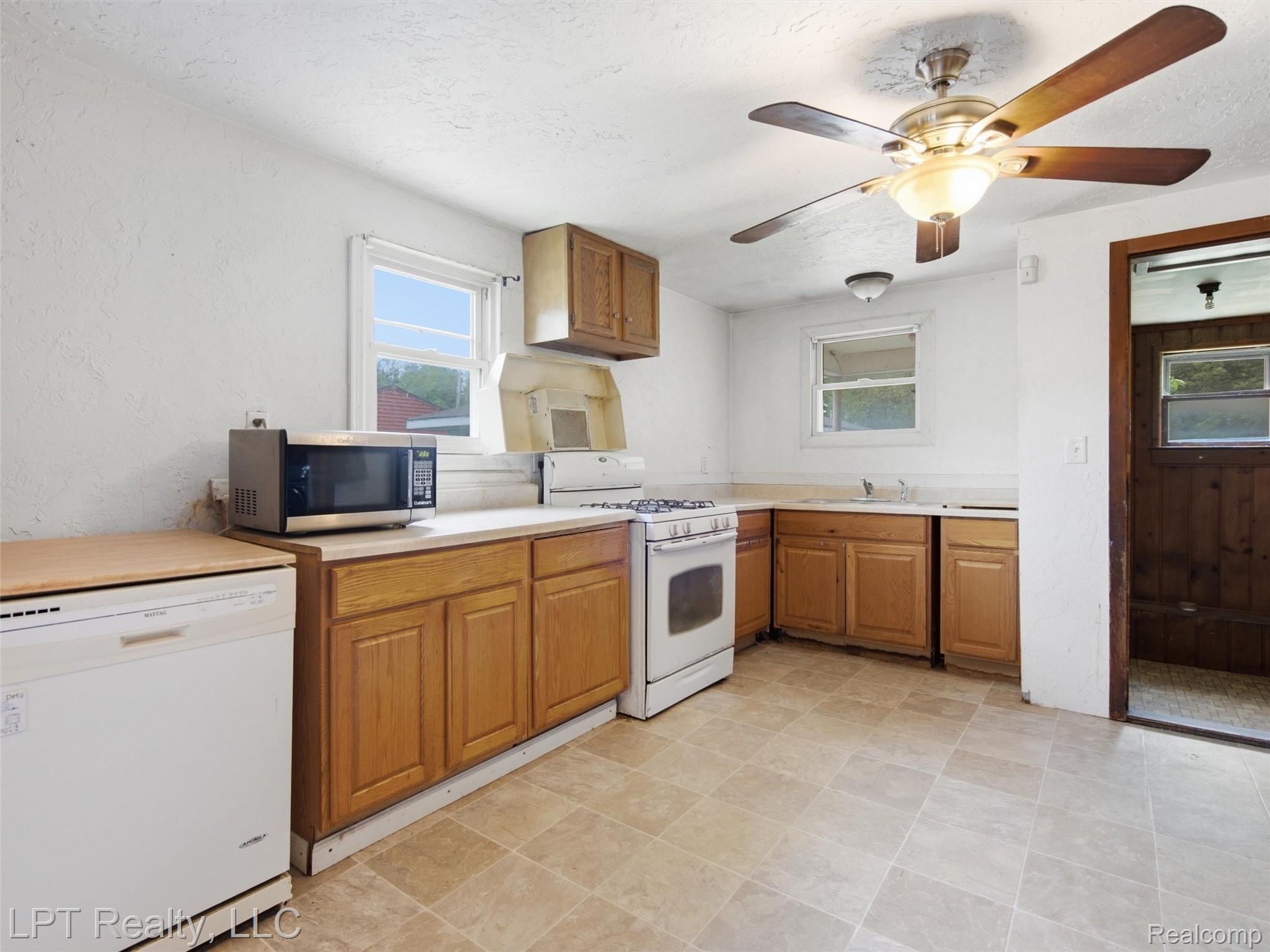 3385 North Genesee Road Flint, MI 48506 - Photo 12 of 24 Kitchen featuring wood cabinetry, white appliances, and a ceiling fan with integrated lighting