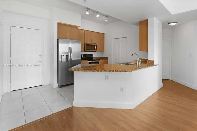 a view of a kitchen with kitchen island a sink wooden floor and a refrigerator