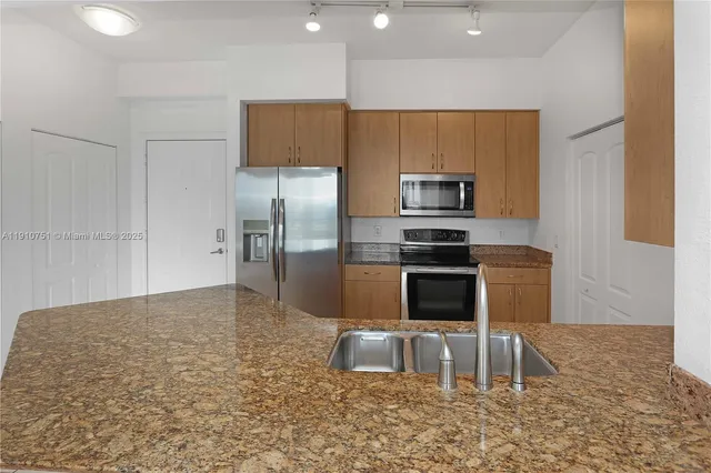 a kitchen with granite countertop a refrigerator and a stove top oven