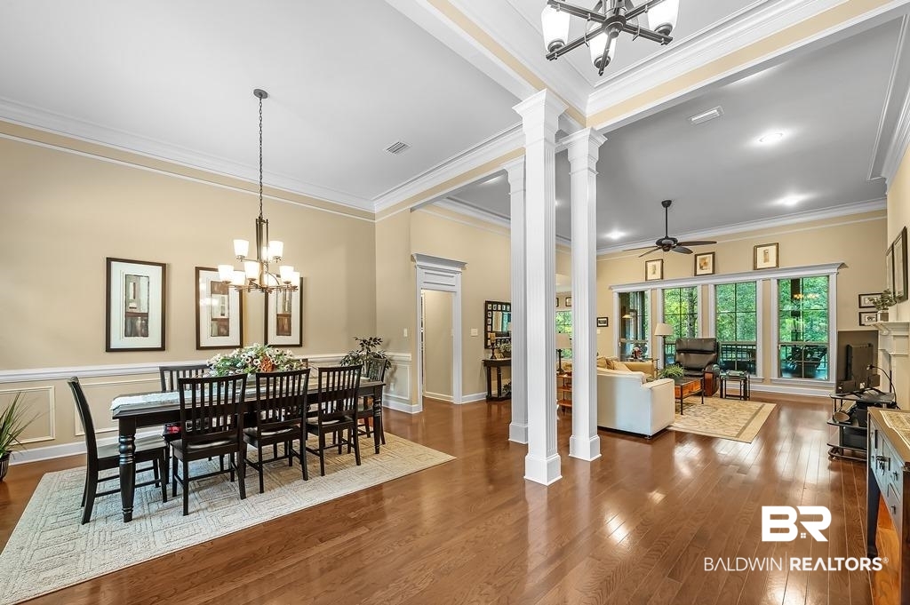 29976 Dolive Ridge Daphne, AL 36527 - Photo 13 of 58 Dining room featuring ornate columns, dark hardwood / wood-style flooring, ceiling fan with notable chandelier, and crown molding