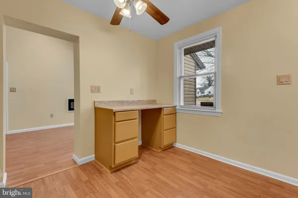 an empty room with wooden floor cabinet and windows