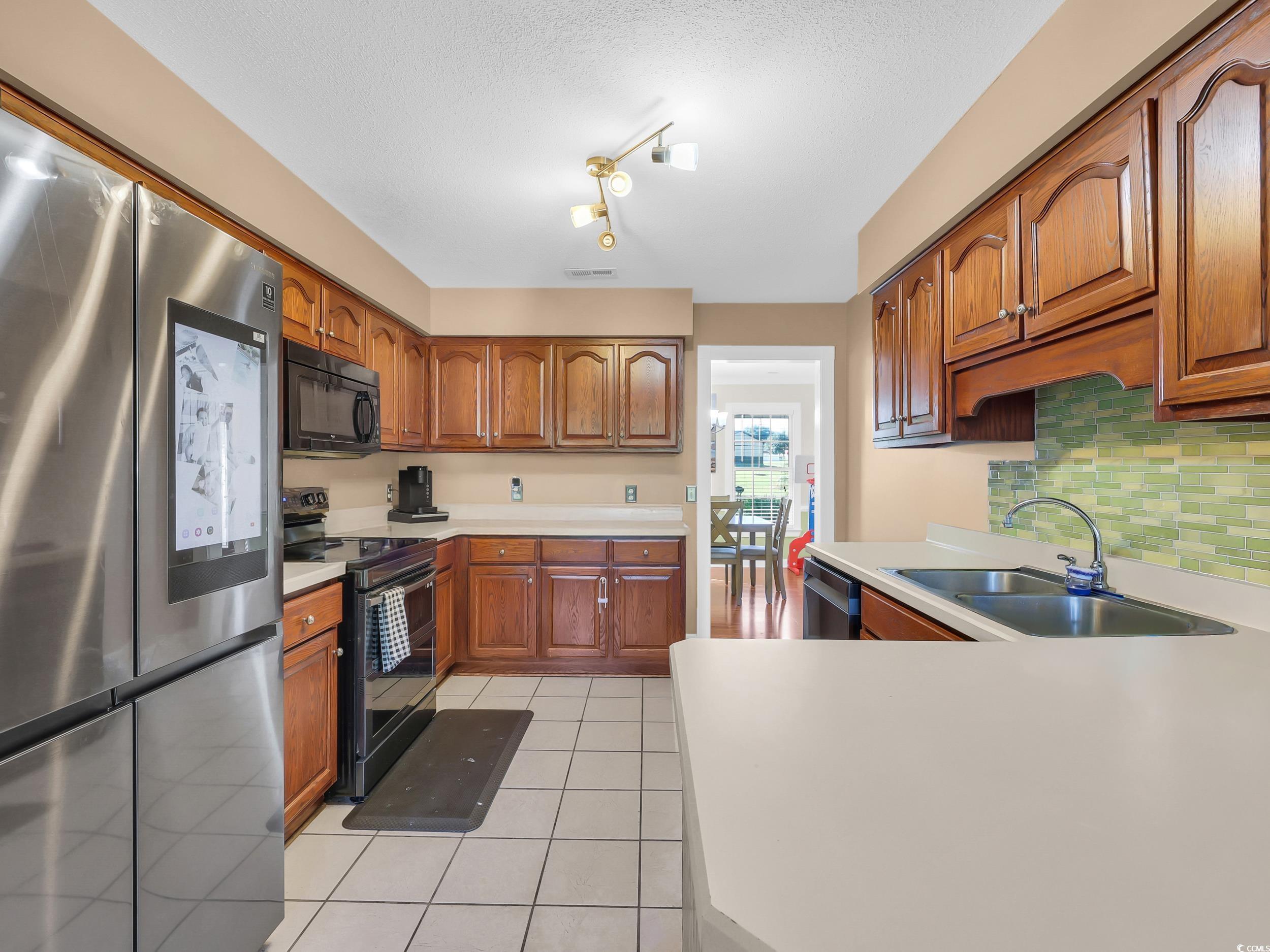 3731 Love Lane Conway, SC 29527 - Photo 11 of 32 Kitchen with black appliances, brown cabinets, light countertops, and light tile patterned floors