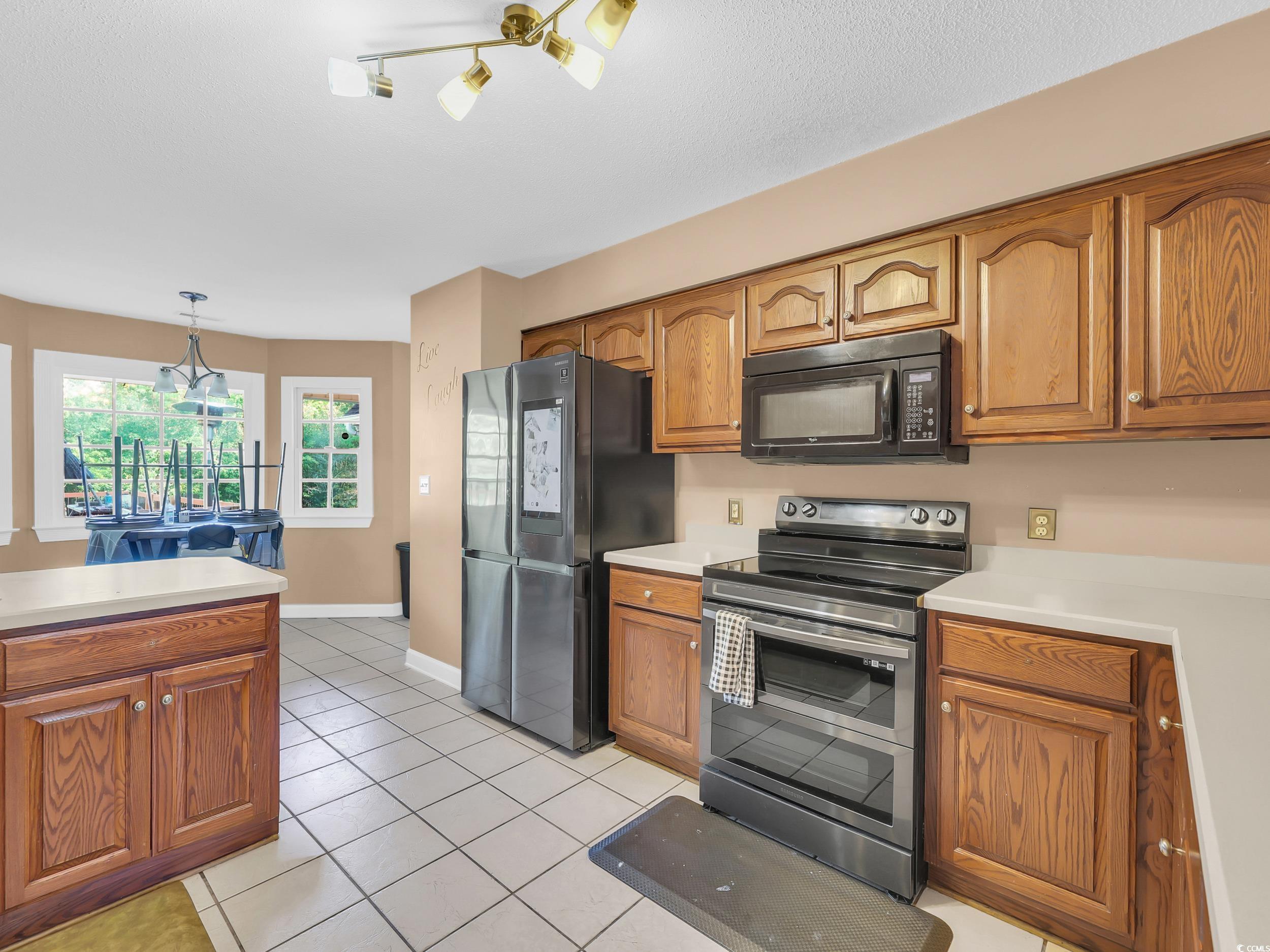 3731 Love Lane Conway, SC 29527 - Photo 12 of 32 Kitchen featuring stainless steel appliances, light countertops, light tile patterned floors, and brown cabinets