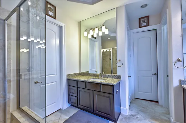 a bathroom with a granite countertop sink a mirror and shower