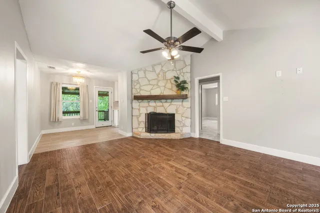 a view of empty room with fireplace and wooden floor
