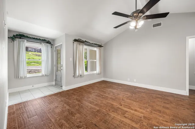 an empty room with windows and fan