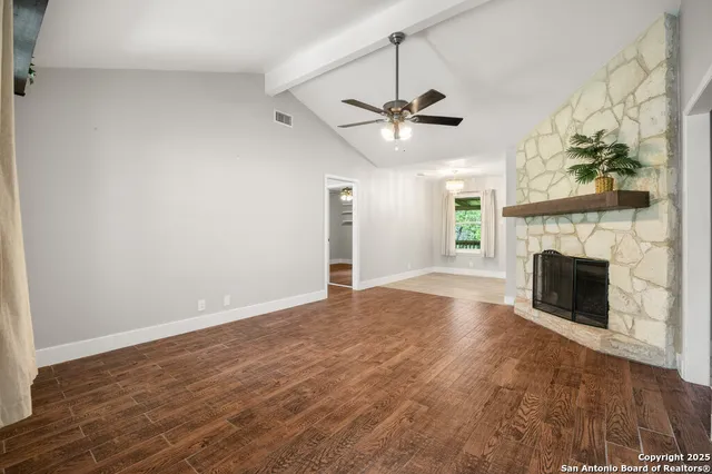 an empty room with windows fireplace and a kitchen view