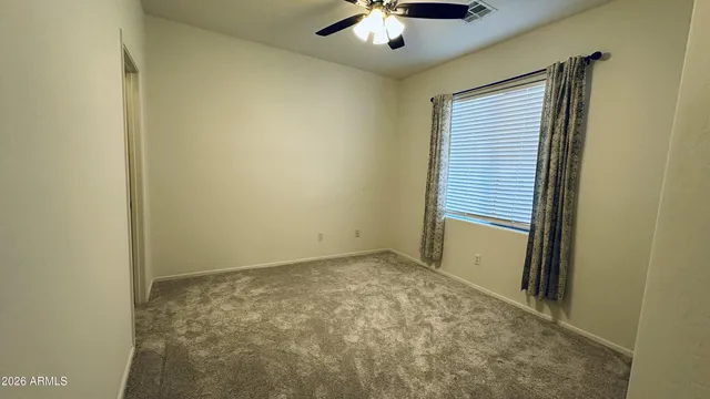 an empty room with a chandelier fan and windows