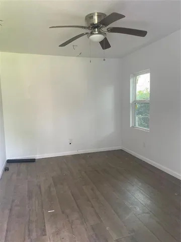 an empty room with a window and a ceiling fan