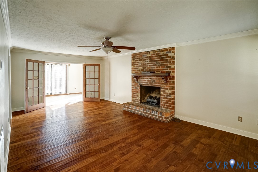 1253 Cardwell Road Crozier, VA 23039 - Photo 15 of 50 an empty room with wooden floor fireplace and windows
