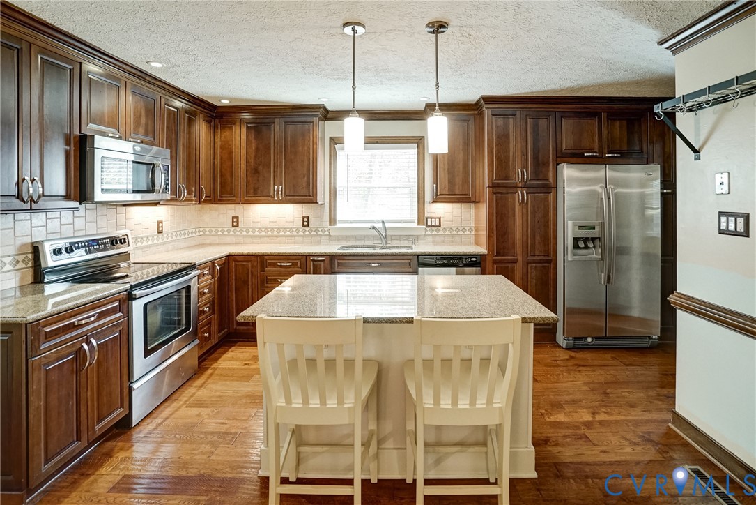 1253 Cardwell Road Crozier, VA 23039 - Photo 28 of 50 a kitchen with stainless steel appliances kitchen island granite countertop a stove a sink and a refrigerator