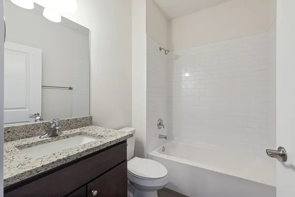 a bathroom with a granite countertop sink a toilet and shower
