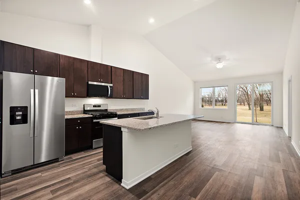 a kitchen with stainless steel appliances a stove a refrigerator a sink a oven with wooden floor and cabinets