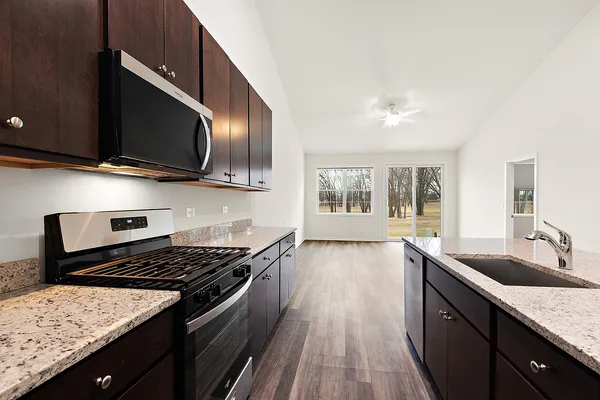 a kitchen with granite countertop wooden cabinets stainless steel appliances and a window