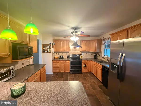a kitchen with stainless steel appliances kitchen island granite countertop a refrigerator a stove a sink and dishwasher