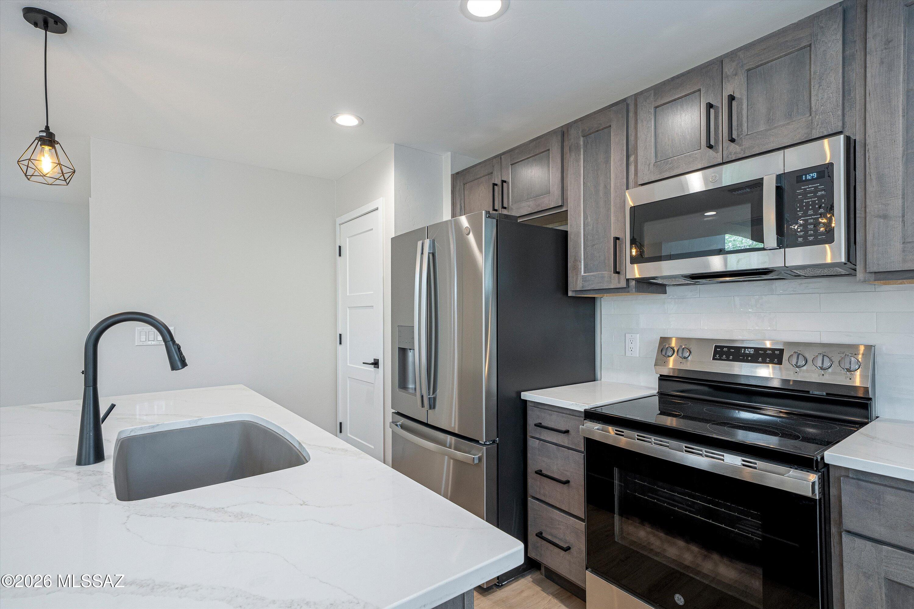 739 North Queen Avenue, Unit 2 Tucson, AZ 85705 - Photo 23 of 28 a kitchen with stainless steel appliances a stove a sink and a microwave