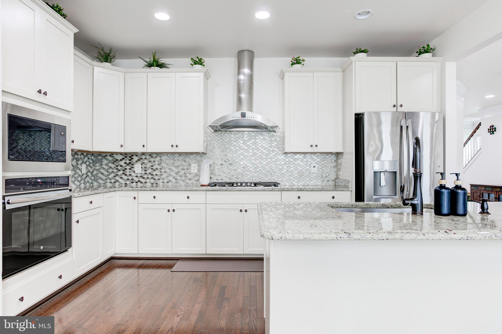 22800 Bubbling Brook Drive Brambleton, VA 20148 - Photo 23 of 64 a kitchen with stainless steel appliances granite countertop a stove a sink and a refrigerator