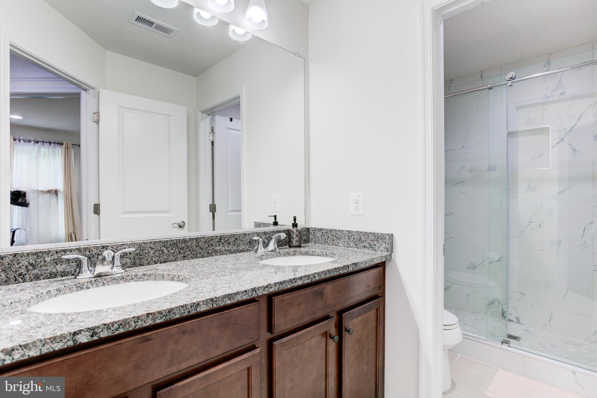 22800 Bubbling Brook Drive Brambleton, VA 20148 - Photo 40 of 64 a bathroom with a granite countertop double vanity sink and mirror with shower