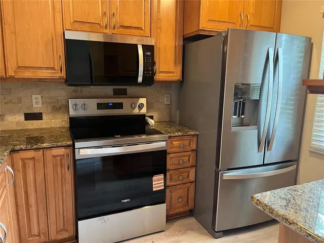 a kitchen with stainless steel appliances granite countertop a refrigerator stove and microwave