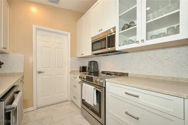 a kitchen with stainless steel appliances granite countertop white cabinets and a stove
