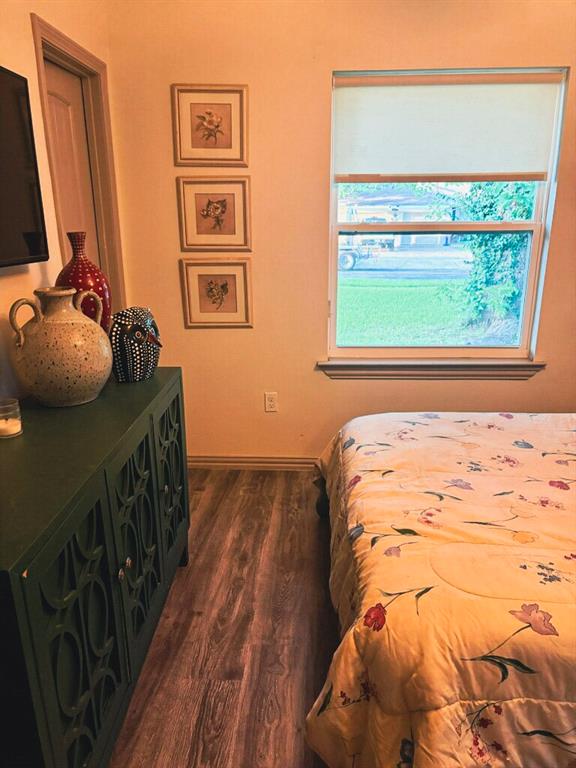 3130 Hillglenn Road Dallas, TX 75228 - Photo 2 of 10 Light-filled room featuring a double-hung window with a roller shade, wood-finish flooring, and a solid core interior door
