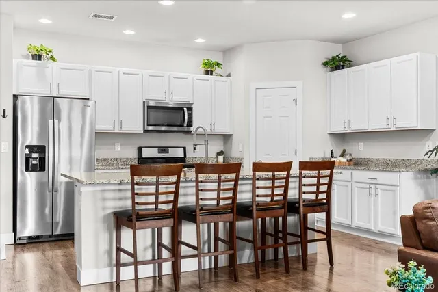 a kitchen with stainless steel appliances granite countertop a stove a refrigerator a microwave a dining table and chairs