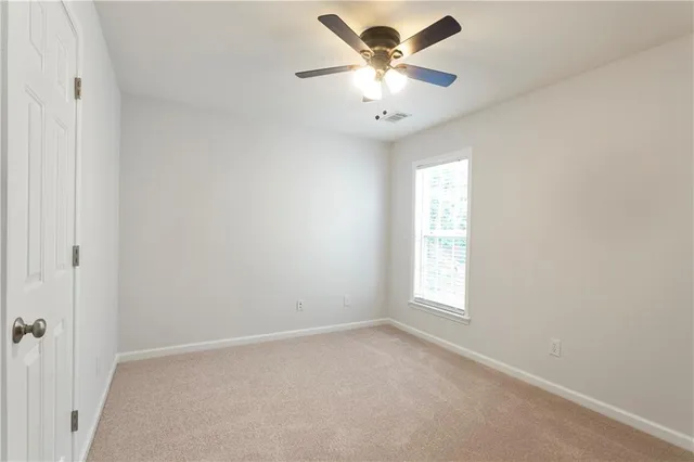 an empty room with a window and a fan