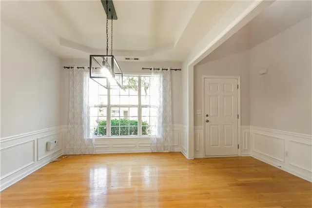 a view of an empty room with window and chandelier fan
