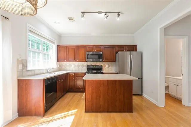 a kitchen with stainless steel appliances granite countertop a refrigerator a stove a sink dishwasher and wooden cabinets with wooden floor