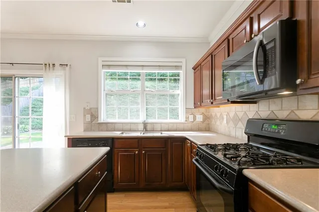a kitchen with stainless steel appliances granite countertop a sink a stove and a microwave