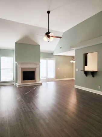 an empty room with wooden floor fireplace and windows
