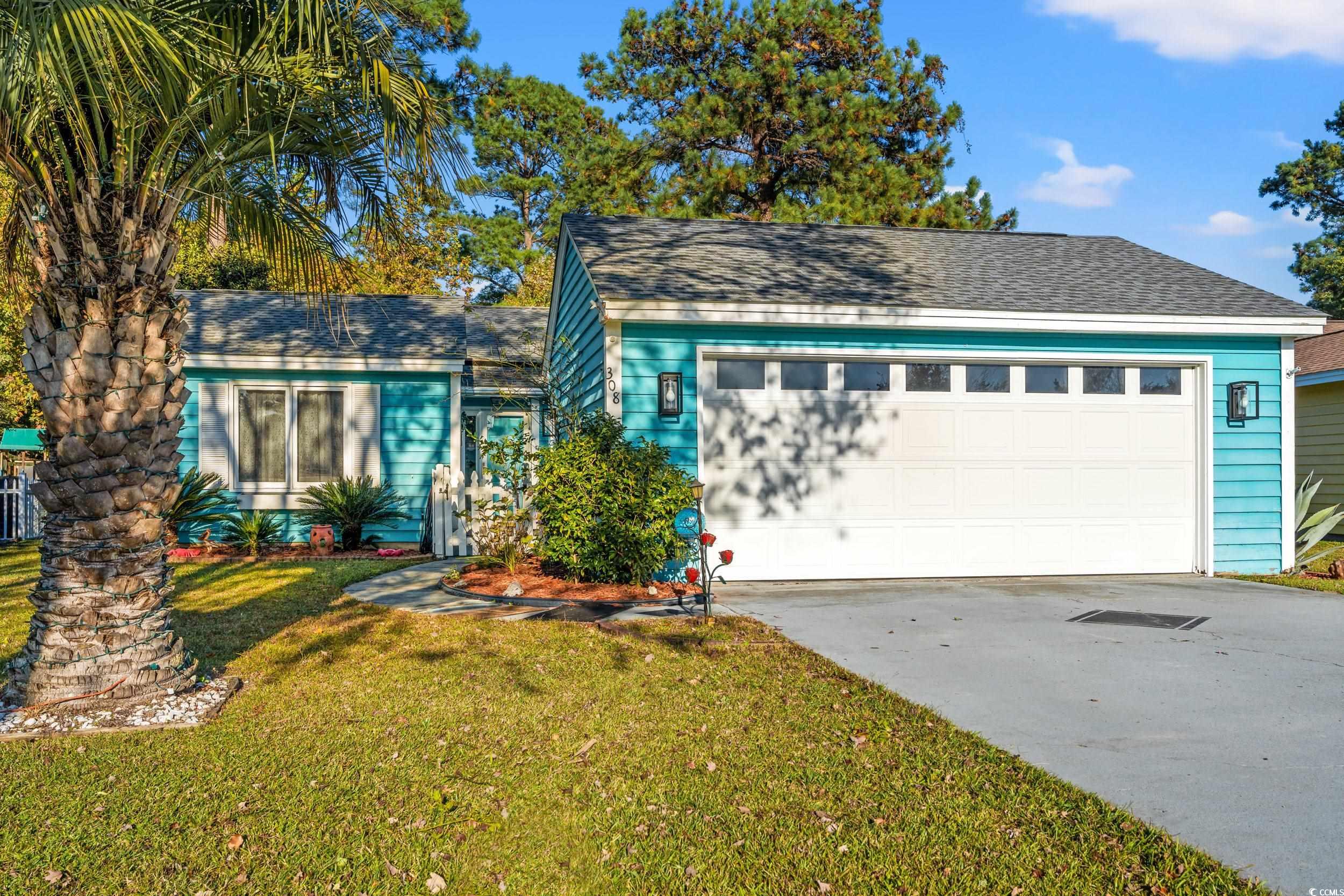 View of front of home with roof with shingles, a front lawn, and concrete driveway