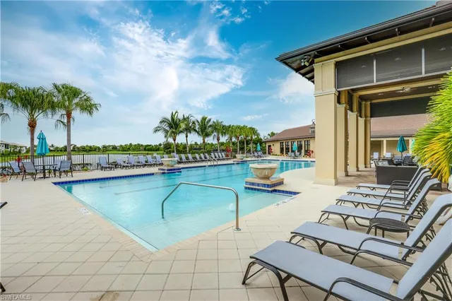 a view of swimming pool with outdoor seating and house in the background