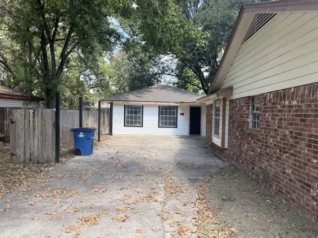 a view of a house with large tree and wooden fence