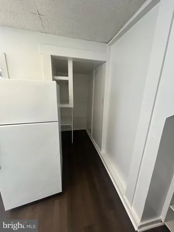 a view of a refrigerator in kitchen and an empty room