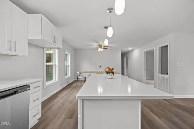 a view with a kitchen island a chandelier wooden floor and a living room