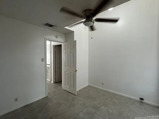 an empty room with a ceiling fan and carpet