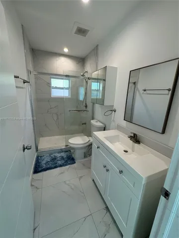a bathroom with a granite countertop sink toilet and shower