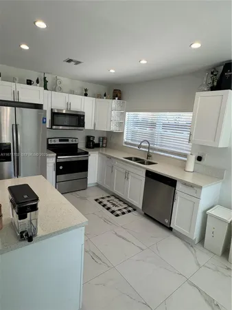 a kitchen with stainless steel appliances a stove a sink a refrigerator and a microwave