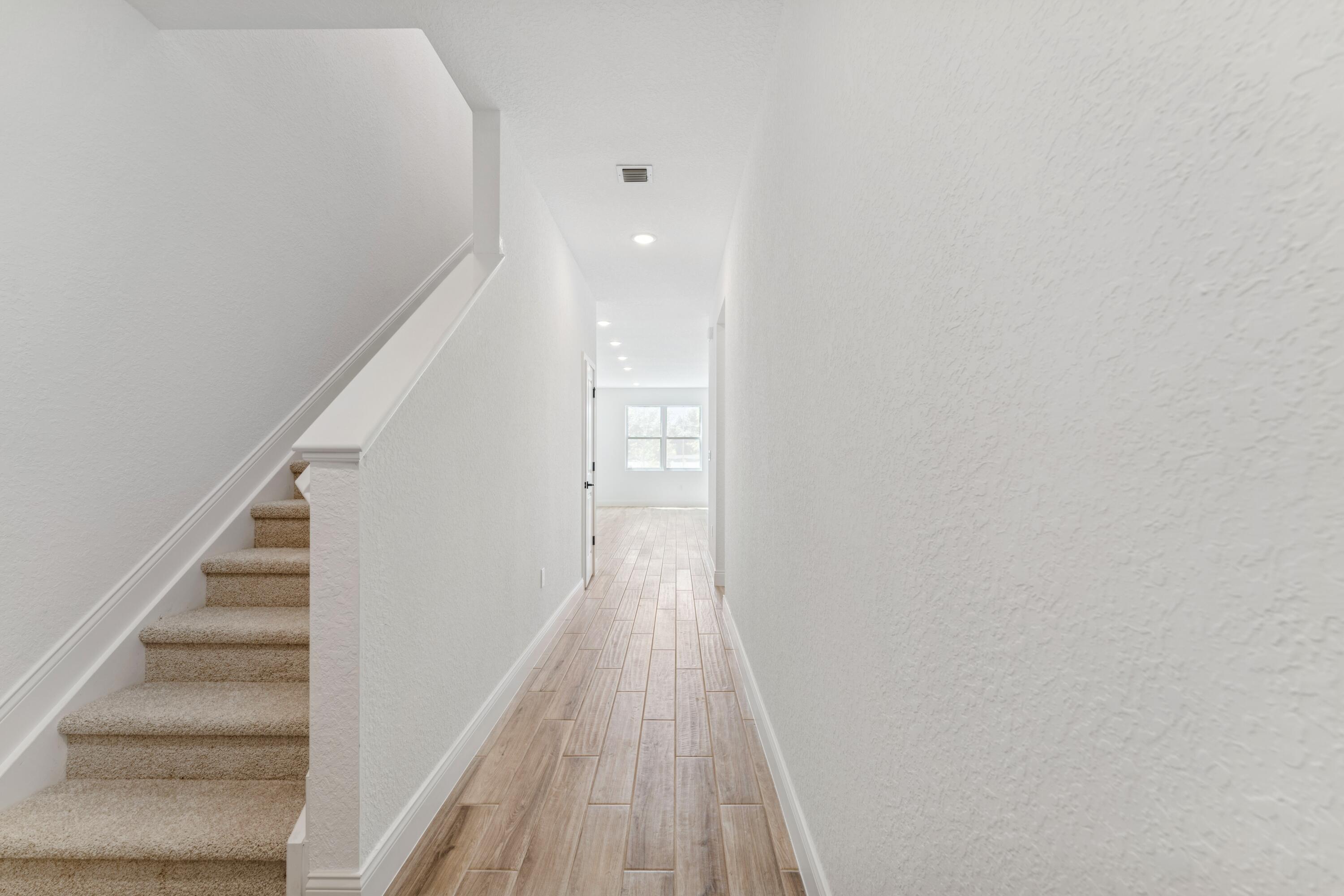 164 Southeast Birch Terrace, Unit 103 Stuart, FL 34997 - Photo 2 of 29 a view of a hallway with wooden floor and staircase